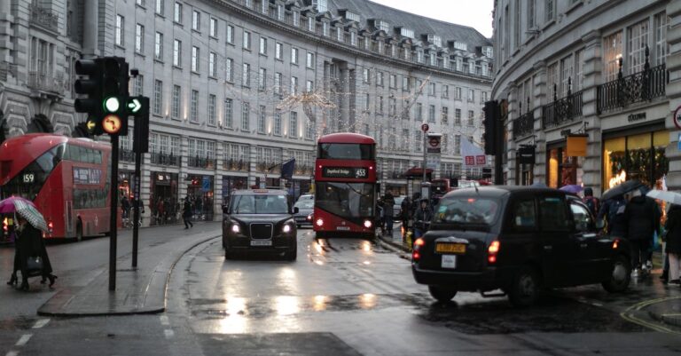 Urban scene of London featuring double decker buses, taxis, and pedestrians in Piccadilly Circus.